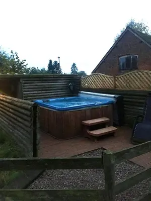 a hot tub with a bench in a backyard at The Sitting Duck in Greet