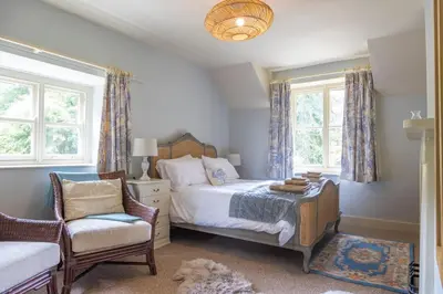 a bedroom with a bed and a chair and windows at 4 bed cottage Breath-taking views Sleeps 8 in Presteigne