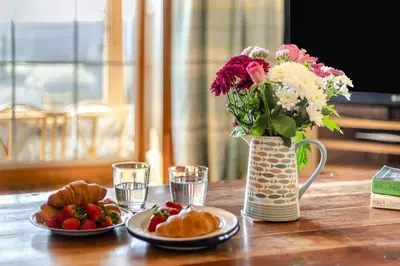 a table with two plates of food and a vase with flowers at 5 Bed in Hundred House oc-l31090 in Hundred House