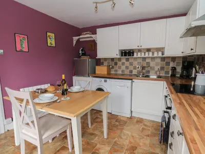 a kitchen with a wooden table and white cabinets at Cantref House Top Floor in Brecon