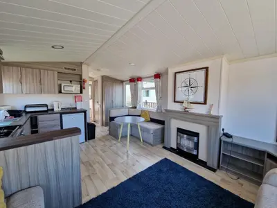 a kitchen and a living room with a fireplace at Sea Breeze Retreat 2 Bedroom Pet Friendly Caravan in Clarach Bay in Aberystwyth