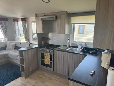 a kitchen with a stove and a sink and a couch at Sea Breeze Retreat 2 Bedroom Pet Friendly Caravan in Clarach Bay in Aberystwyth