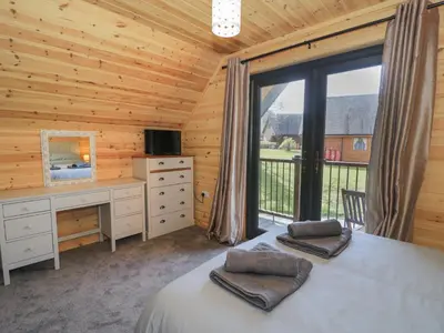 a bedroom with a bed and a desk and a window at Sunset Lodge 5 in Llanbedr