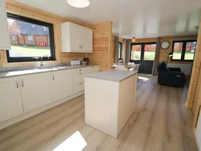 a kitchen with white cabinets and a large window at Sunset Lodge 5 in Llanbedr