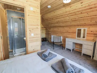 a bedroom with a bed and a desk in a log cabin at Sunset Lodge 5 in Llanbedr