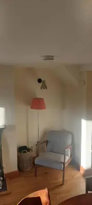 a living room with a chair and a lamp at Cosy cottage in Snowdonia hamlet in Frongoch