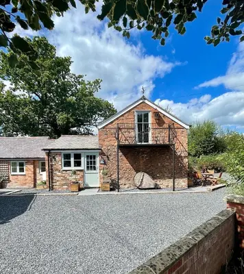 an exterior view of a brick house with a garage at The Old Smithy, beautifully restored cottage in Carreghofa, near Llanymynech in Llanymynech