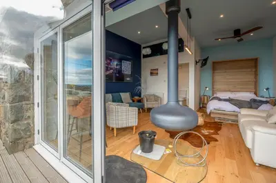 a living room with a large window and a room with a fireplace at Bermo Cwtch in Barmouth