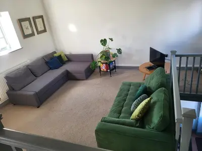 a living room with a green couch and a television at North Cottage in Berriew