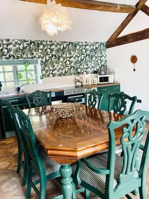 a kitchen with a wooden table and green chairs at North Cottage in Berriew