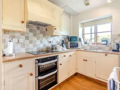a kitchen with white cabinets and a stove top oven at Swallow's Nest in Craven Arms