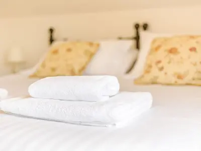 two towels are stacked on a white bed at Robin's Nest in Craven Arms