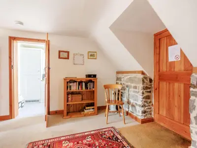 a living room with a stone fireplace and a wooden door at Robin's Nest in Craven Arms