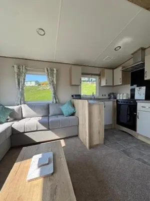 a living room with a couch and a kitchen at The Harlech, Penygraig Caravan Park in Borth
