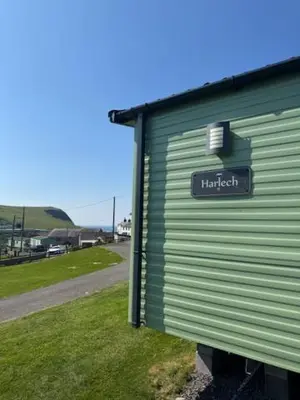 a green building with a sign on the side of it at The Harlech, Penygraig Caravan Park in Borth
