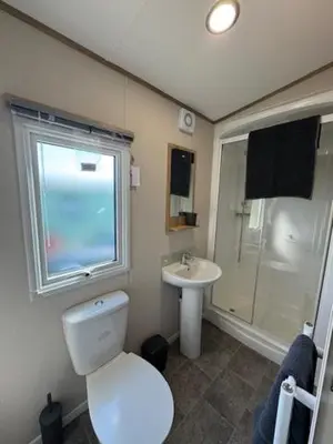 a bathroom with a toilet and a sink and a window at The Harlech, Penygraig Caravan Park in Borth