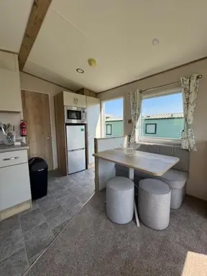 a kitchen with a table and two stools in it at The Harlech, Penygraig Caravan Park in Borth