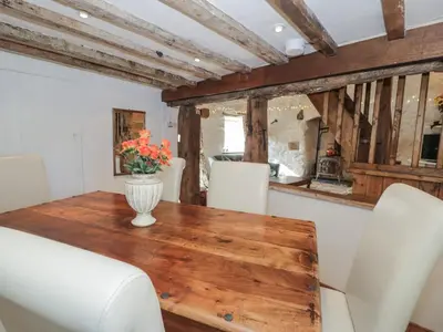 a dining room table with white chairs and a vase with flowers at Old Ty'n Y Wern in Bala