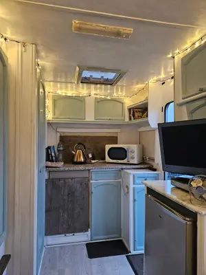an rv kitchen with blue cabinets and a microwave at Cosy Caravan Walkers Ramblers Fishermen Cyclists in Abermule