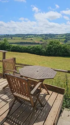 a wooden table and bench sitting on a wooden deck at Cosy Caravan Walkers Ramblers Fishermen Cyclists in Abermule