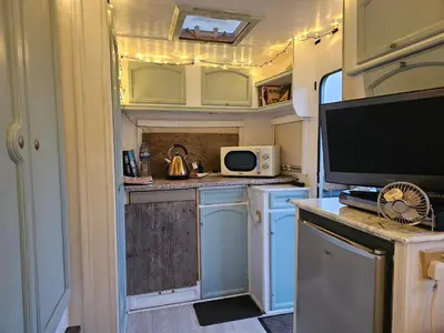 an rv kitchen with blue cabinets and a tv at Cosy Caravan Walkers Ramblers Fishermen Cyclists in Abermule