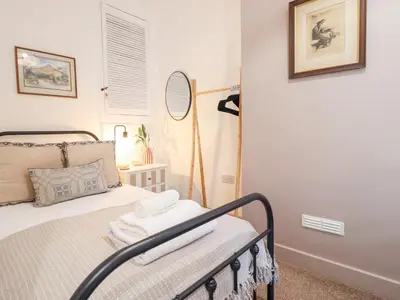 a small room with a bed with a mirror and a mirror at Derwen House in Llangollen