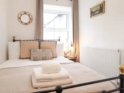 a bedroom with a white bed with a window at Derwen House in Llangollen