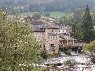 a building next to a river with a bridge at Derwen House in Llangollen