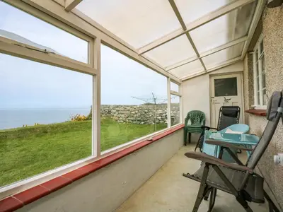 a screened in porch with windows and a table and chairs at Tegawelon in Harlech