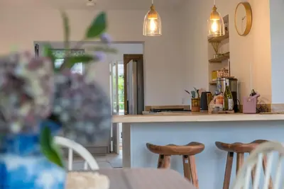 a kitchen with a counter with chairs and a table at Glanaber in Dyffryn