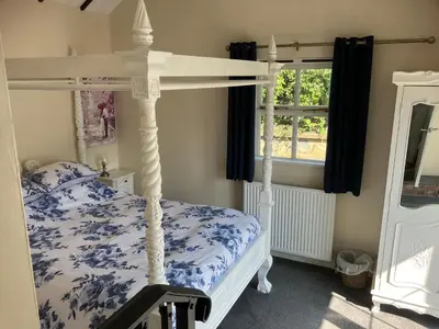 a bedroom with a white canopy bed with blue flowers at Blue Lodge - by the sea, sauna, BBQ, private garden and parking in Aberystwyth