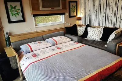 a living room with a bed and a couch at POD4 Family Glamping with seaview & Wi-Fi in Llwyngwril