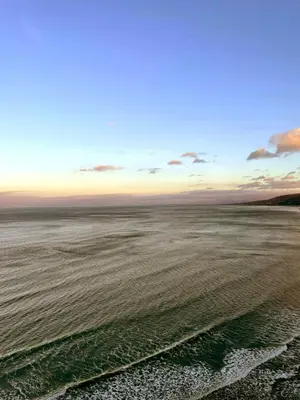 a view of the ocean from a beach at sunset at POD4 Family Glamping with seaview & Wi-Fi in Llwyngwril