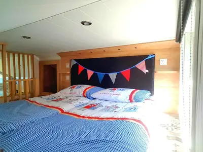a bedroom with a bed with a blue comforter and pillows at POD4 Family Glamping with seaview & Wi-Fi in Llwyngwril