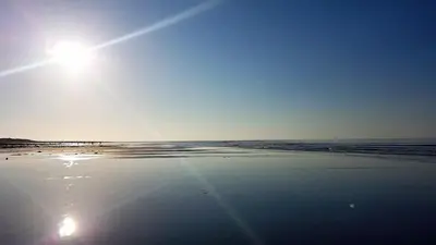 a beach with the sun shining on the sand at POD6 Family Glamping with seaview & Wi-Fi in Llwyngwril