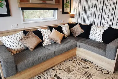 a couch with pillows on it in a living room at POD6 Family Glamping with seaview & Wi-Fi in Llwyngwril