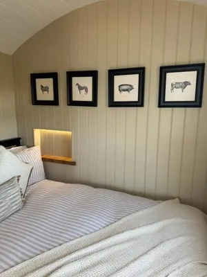 a bedroom with four pictures of animals on the wall at coastal view shepherds hut with hot tub in Llanfair
