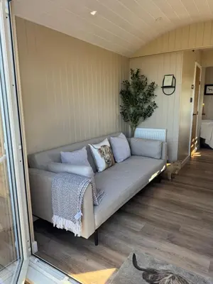 a living room with a couch in a room at coastal view shepherds hut with hot tub in Llanfair