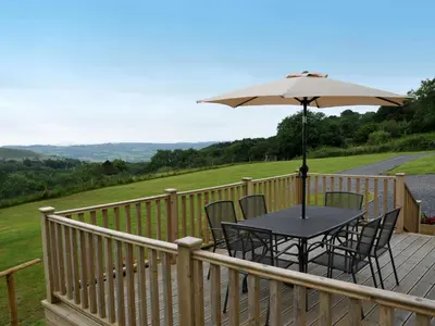 a table and chairs on a deck with an umbrella at Llaethdy Rachel Lampeter in Aberaeron