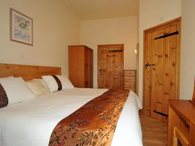 a bedroom with two beds with wooden cabinets and a door at Llaethdy Rachel Lampeter in Aberaeron