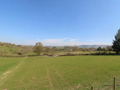 a field with a fence in the foreground at Llety Cariad in Llandrindod Wells