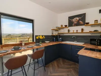 a kitchen with blue cabinets and a large window at Bryn Hafod in Llandrindod Wells