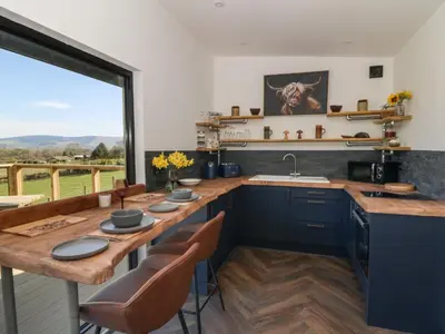 a kitchen with a wooden table and a large window at Bryn Hafod in Llandrindod Wells