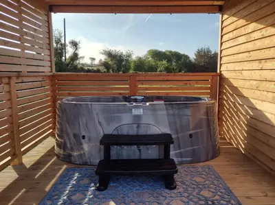 a jacuzzi tub on a deck with a stool at Fir Tree Shepherd's Hut in Llanon