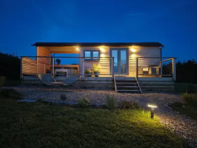 a small house with lights on the front of it at Fir Tree Shepherd's Hut in Llanon