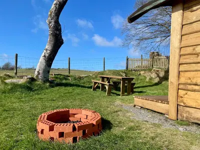 a brick bed in the grass next to a picnic table at The Viking Lodge with Sauna in Ystrad-Meurig