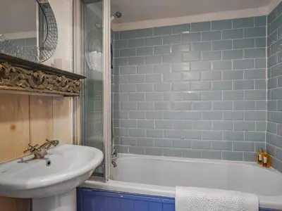 a bathroom with a white tub and a sink at Flo's Cottage in Kington