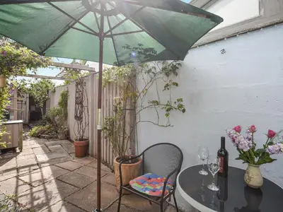 a table with a green umbrella on a patio at Flo's Cottage in Kington
