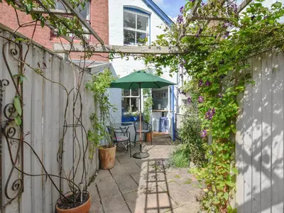 a patio with an umbrella and a table at Flo's Cottage in Kington