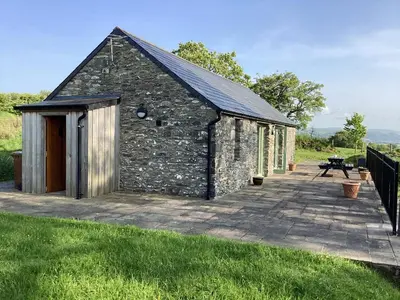 a stone building with a patio in the grass at Cwtch in Ystrad Meurig